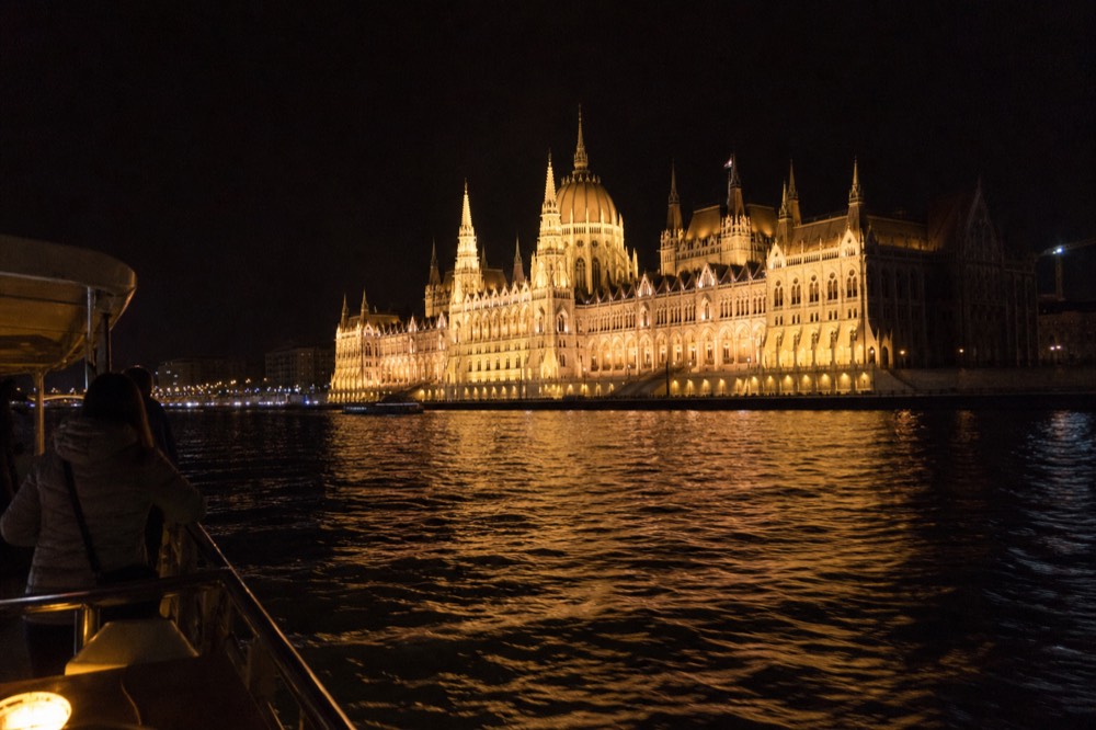 Illuminated Hungarian Parliament building seen from a boat on the Danube at night, no text, no logos, no people