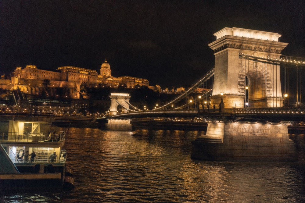 Chain Bridge lit at night with Buda Castle on the hill behind it viewed from mid-river, no text, no logos, no people